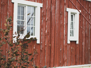 Red rustic wooden barn facade and stone foundation with white window
