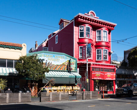 Haight Ashbury, San Francisco - USA: Jimi Hendrix Red House on Haight Street in full sun with colorful Haight Street Market sign and produce next door