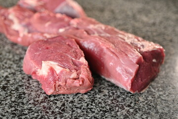 slices of red sliced beef meat, beef tenderloin, red meat on a grey background 	