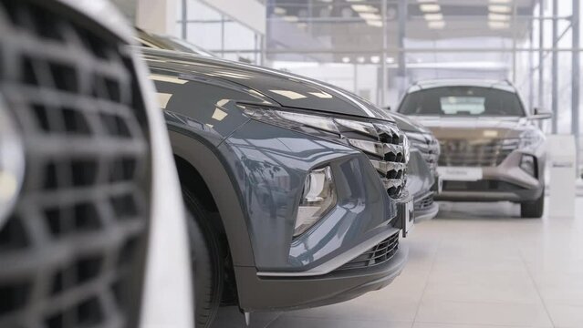 Car dealership with row of anonymous new vehicle on sale. Showroom with shiny auto. Automotive