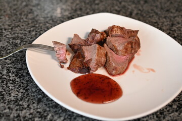 veal steak roasted medium rare in used dishes with red sauce 