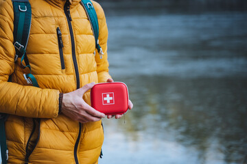 First aid kit on the background of a yellow jacket, a travel first aid kit, a hard box with...