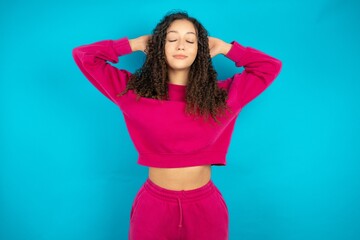 Close up portrait of Beautiful young girl wearing pink tracksuit on blue background who dreams...