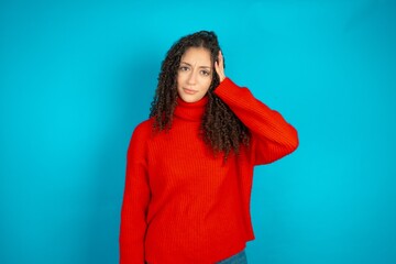beautiful teen girl wearing red knitted sweater tries to memorize something, keeps fore finger on...