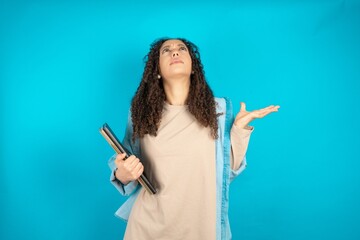 Young beautiful teen woman crazy and mad shouting and yelling with aggressive expression and arms raised. Frustration concept.