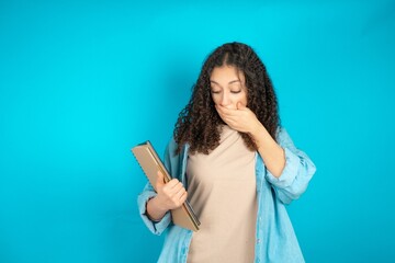 Shocked beautiful teen girl wearing denim jacket look surprisedly down, indicates at blank  with...