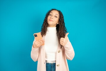Portrait of beautiful teen girl wearing brown cardigan using and texting with smartphone  happy...