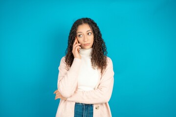 Sad beautiful teen girl wearing brown cardigan  talking on smartphone. Communication concept.