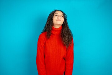 Beautiful teen girl wearing knitted red sweater over blue background very happy and excited about...