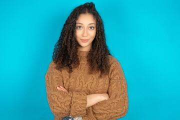 Self confident serious calm beautiful teen girl wearing brown knitted sweater stands with arms...