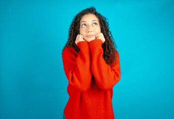 Portrait of sad beautiful teen girl wearing red knitted sweater hands face look empty space