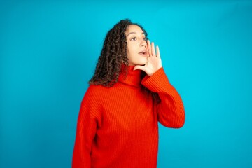 beautiful teen girl wearing red knitted sweater look empty space holding hand face and screaming or calling someone. - obrazy, fototapety, plakaty