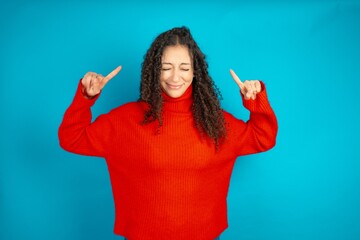 Photo of crazy beautiful teen girl wearing red knitted sweater screaming and pointing with fingers...