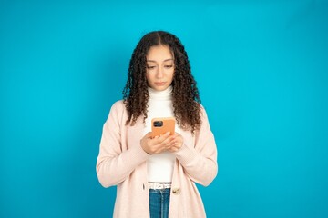 Focused Beautibul teen girl wearing casual clothes use smartphone reading social media news, or...