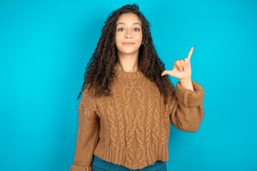 Beautiful teen girl wearing knitted sweater over blue background showing up number six Liu with fingers gesture in sign Chinese language