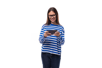 charming young slender caucasian woman with straight dark hair in a blue sweater uses a smartphone to watch a video