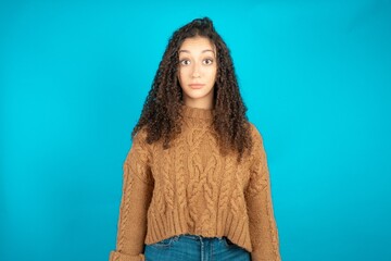 Stunned beautiful caucasian teen girl wearing brown sweater stares reacts on shocking news....