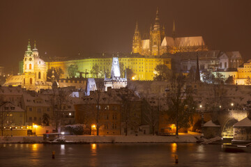 Fototapeta na wymiar Night colorful snowy Christmas Prague Lesser Town with gothic Castle and Charles Bridge, Czech republic