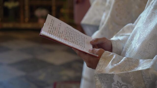 Priest holds a gospel book or Bible and reads a prayer. Christianity or Catholicism, faith in God. Church rite, liturgy.
