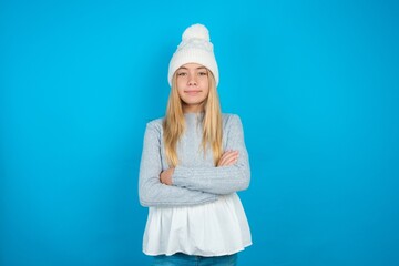 Dreamy rest relaxed Teen caucasian girl wearing blue knitted sweater and woolly hat crossing arms,