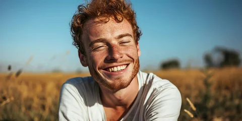 Fotobehang young man with red hair an freckles sitting in a field © Karat