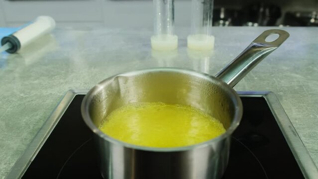 Boiling mixture of fruit juice and flavored spices in saucepan on stove. Preparation of ingredients for molecular cuisine dish