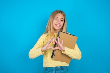 Fototapeta premium Serious beautiful caucasian teen girl wearing yellow sweater keeps hands crossed stands in thoughtful pose concentrated somewhere