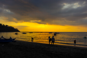 Fototapeta premium The tourists are enjoying sunset in the Nipah beach, West Nusa Tenggara, Indonesian tourism object.