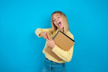Nice addicted cheerful beautiful caucasian teen girl wearing yellow sweater using gadget playing network game