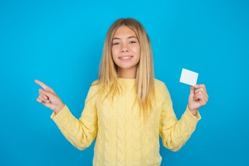 Smiling MODEL showing debit card pointing finger empty space
