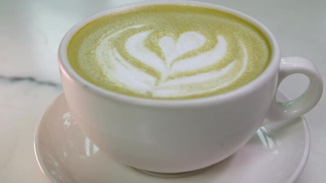 Waiter puts hot matcha tea with green foam on table. Alternative to cappuccino to reduce your caffeine intake and replace it with healthier macha tea. Consumption of Japanese macha tea by vegetarians