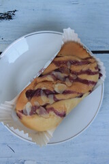 Torn bread topped with blueberry jam with peanut sprinkles wrapped in a paper cup on a plate on the table