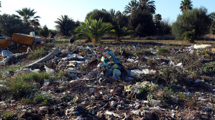 A lot of garbage in nature, rags, paper, scraps of fabric on a beautiful tropical landscape among palm trees, environmental pollution 