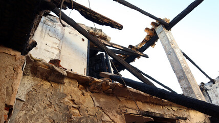 Ruins of a house after a fire, burnt house, charred ceilings, destroyed walls, garbage