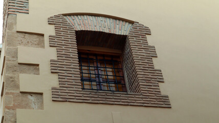 Window with black wrought iron grille framed by antique stonework, Spain