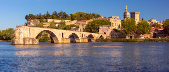 Fototapeta na wymiar Famous medieval Saint Benezet bridge and Palace of the Popes during gold hour, Avignon, France