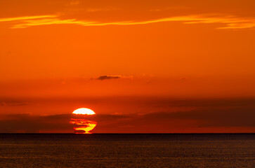 赤く染まる空と水平線に沈むだるま夕陽