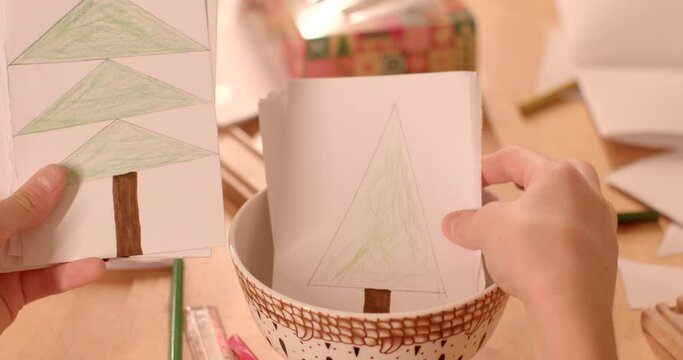Close-up kids hands with pictures of fir trees. Paper crafts as way for children to immerse themselves in spirit of Christmas and New Year's festivities. Creative activities associated holiday season.