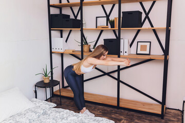 woman doing stretching exercises at home, as part of a healthy lifestyle without going to the gym.