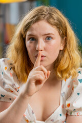 Keep my secrets, silence. Redhead woman whisper news rumors holding hands near mouth, share gossip,...