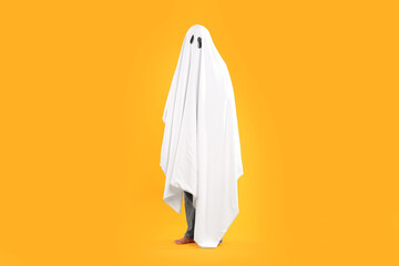 Woman in white ghost costume on yellow background. Halloween celebration