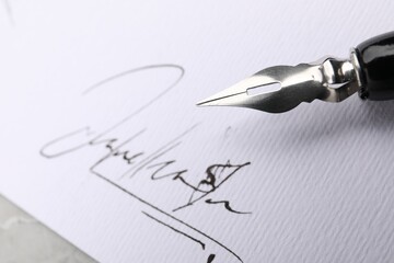 Sheet of paper with signature and fountain pen at table, closeup