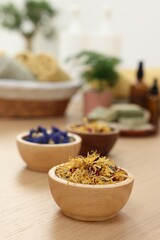 Bowls of dry flowers on light wooden table. Spa therapy