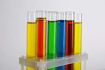 Test tubes with liquids in stand on white background, closeup