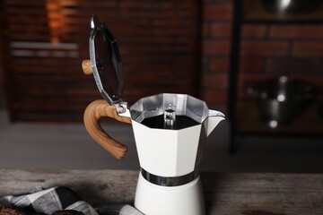 Aromatic coffee in moka pot on wooden table, closeup