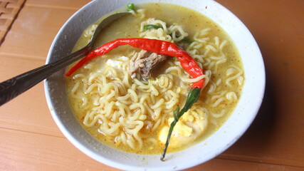 A bowl of delicious boiled noodles with red pepper on top.
