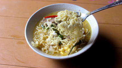  A bowl of delicious boiled noodles with red pepper on top.