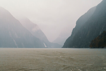 Photograph of low hanging clouds over mountains in Milford Sound in Fiordland National Park on the...