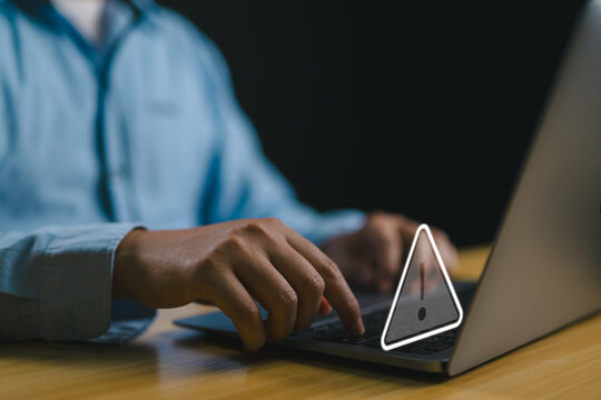 User working on laptop computer with triangle caution warning sign for notification error and maintenance concept, computer virus detected, personal data protection, network security.