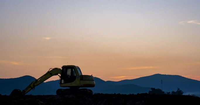 Time-lapse of a Silhouette Backhoe in a construction site from dawn to sunrise with dolly-in shot.